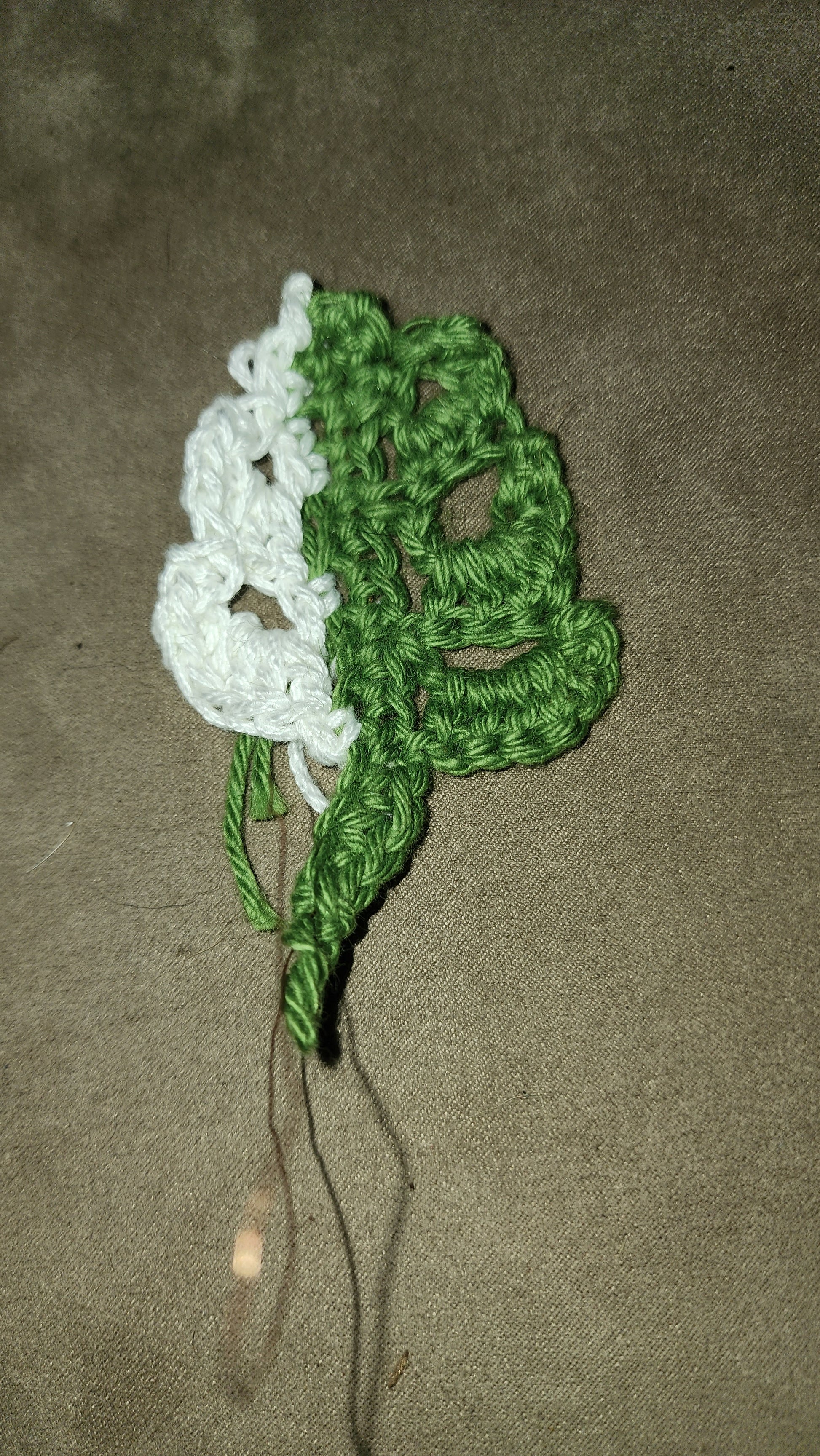 The FAS Plant Charms feature a small crochet flower made with white petals and green leaves on brown fabric—visible yarn ends add charm, making it ideal for plant straps or pairing with polished wood decor.